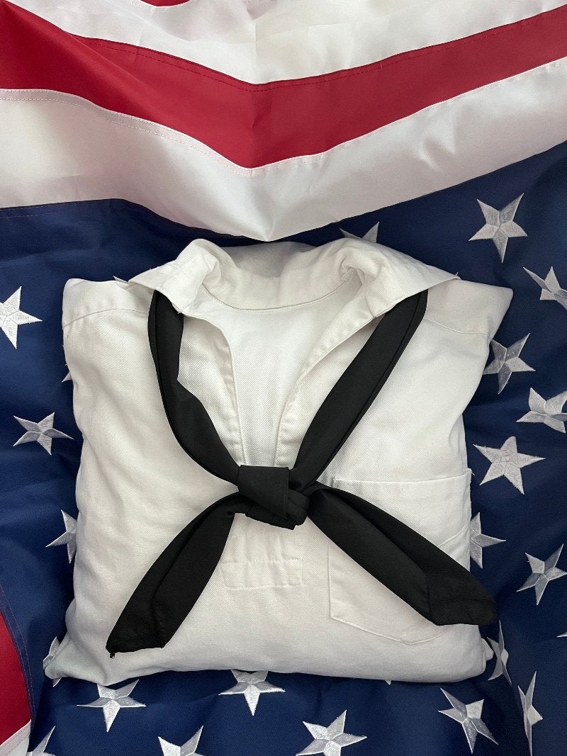 white vintage navy shirt made into a memory pillow laying on the American flag.