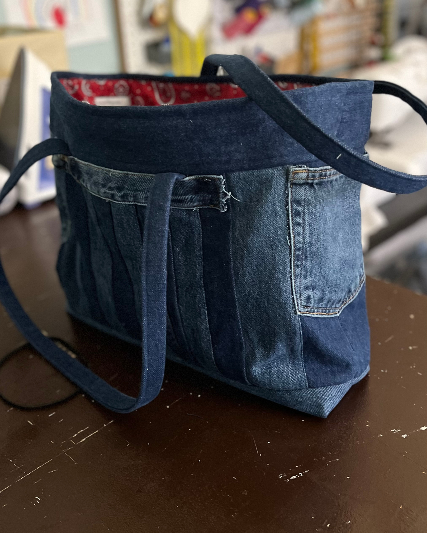 Large denim tote with red lining sitting on a table.