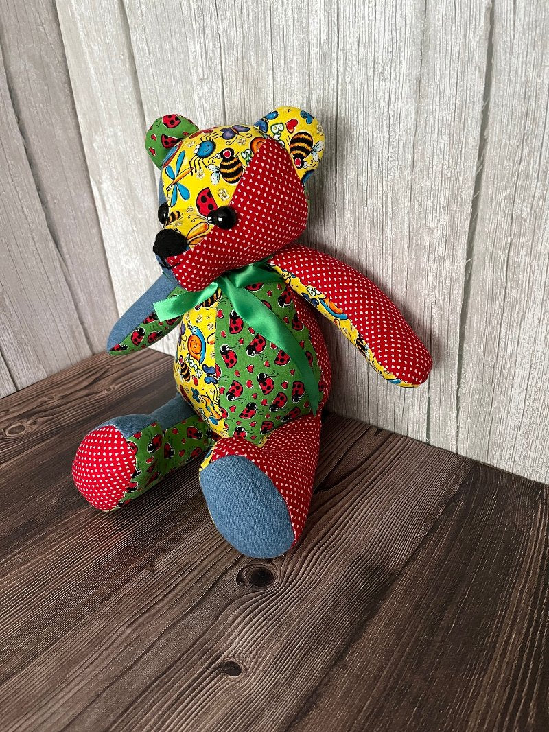 14 inch patchwork memory bear made from four different patterns of scrap fabrics, blue, yellow, red, and green.