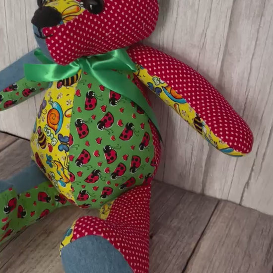 Video of 14 inch patchwork memory bear made from four different patterns of scrap fabrics, blue, yellow, red, and green.