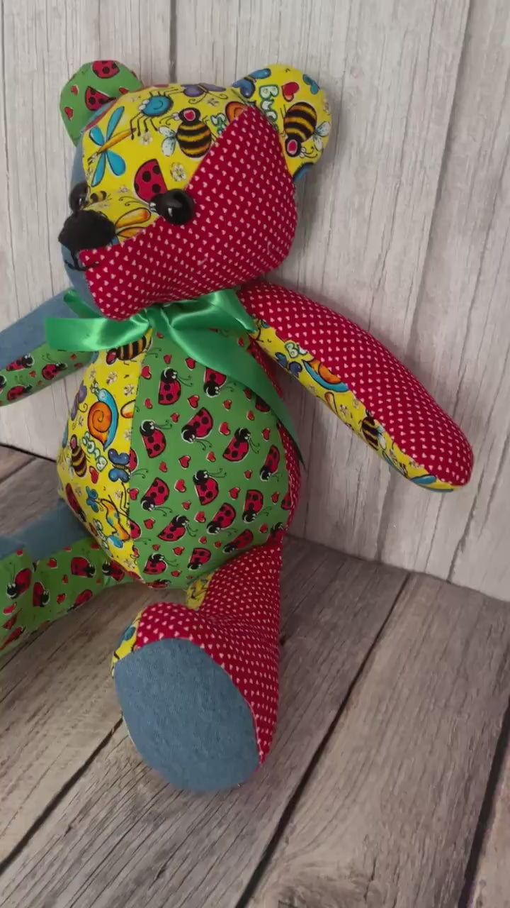 Video of 14 inch patchwork memory bear made from four different patterns of scrap fabrics, blue, yellow, red, and green.